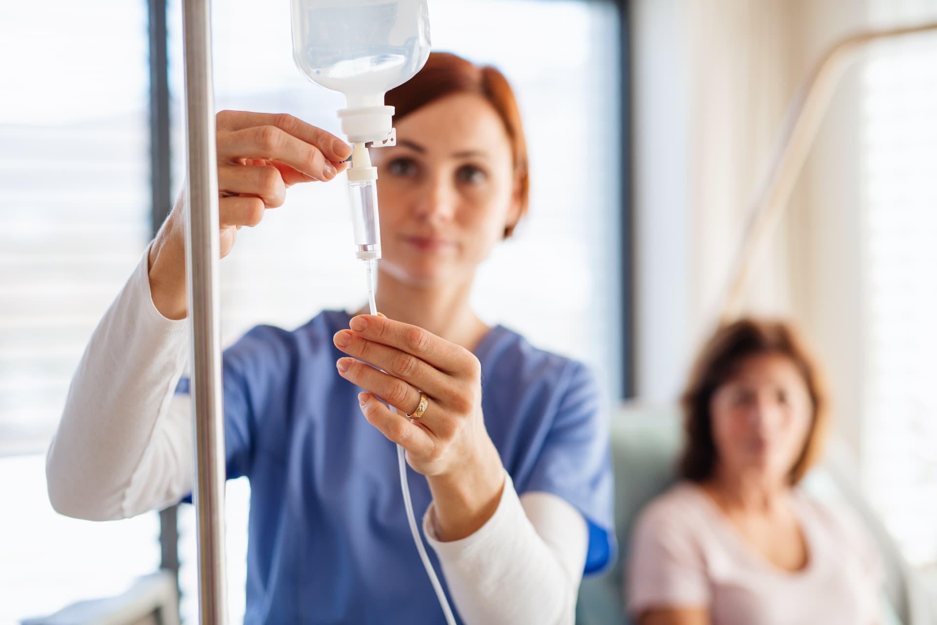 A clinician's hands placing an IV line for a patient receiving infusion care